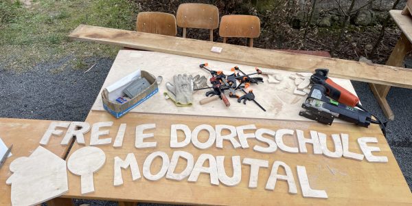 auf einem Tisch im grünen sind aus Holz geschnittene Buchstaben "Freie Dorfschule Modautal"